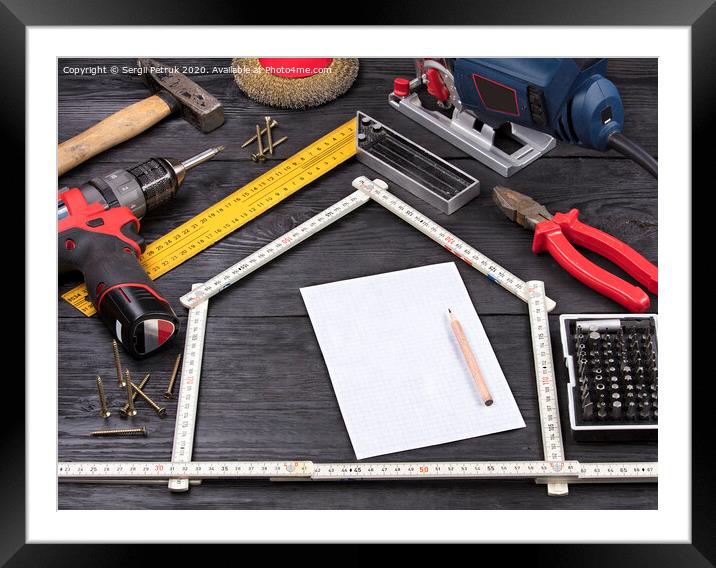 Tool for construction and repair on a black wooden background around a white sheet of paper with a pencil Framed Mounted Print by Sergii Petruk