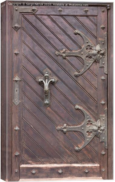 Ancient antique wooden doors with wrought iron loops and cross bars. Canvas Print by Sergii Petruk