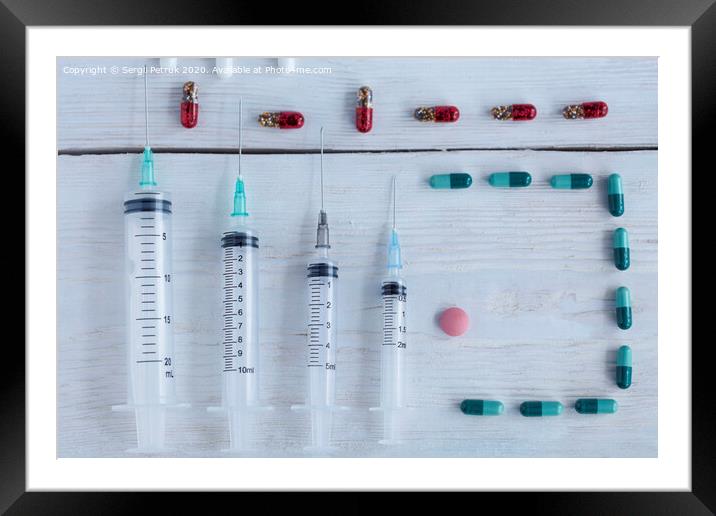 Medical syringes, capsules, pills lie vertically on a white roughly painted wooden table. Framed Mounted Print by Sergii Petruk