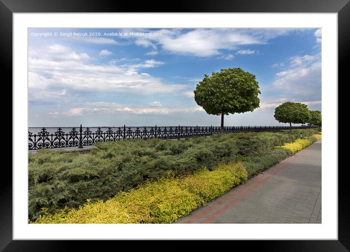 A cobbled stepped path along the embankment of the river, framed by a metal decorative fence cut off by bushes and trees in a beautiful park Framed Mounted Print by Sergii Petruk