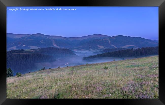 A green meadow and a gray curly fog on a hill in the background of the Carpathian Mountains in the early morning Framed Print by Sergii Petruk