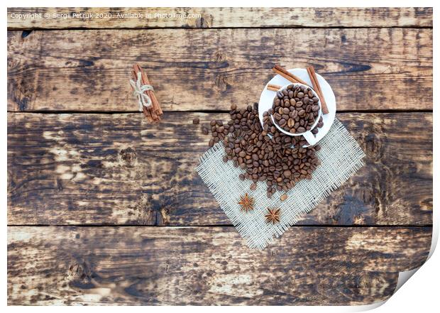 Grain coffee in a cup, which stands on a sackcloth from burlap. Cinnamon on a platter and tied with a rope. Anise stars complement the aroma of coffee. View from above. Print by Sergii Petruk