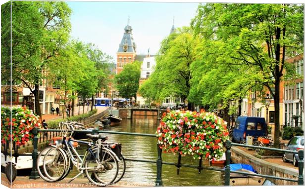 A bicycle parked on the side of a river in Amsterd Canvas Print by M. J. Photography