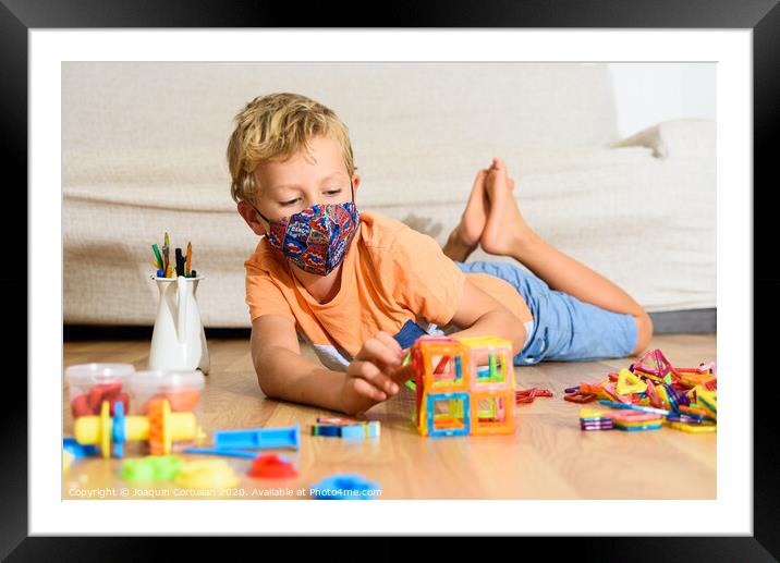 Young child plays at home with mask while recovering from covid infection. Framed Mounted Print by Joaquin Corbalan