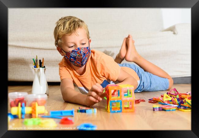 Young child plays at home with mask while recovering from covid infection. Framed Print by Joaquin Corbalan