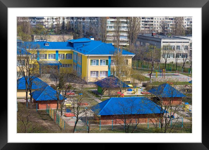 Bright blue roof of kindergarten against the background of gray urban high-rise buildings Framed Mounted Print by Sergii Petruk