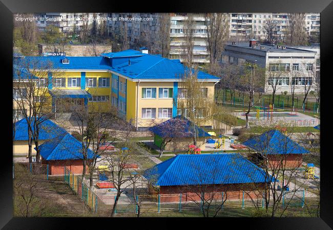 Bright blue roof of kindergarten against the background of gray urban high-rise buildings Framed Print by Sergii Petruk