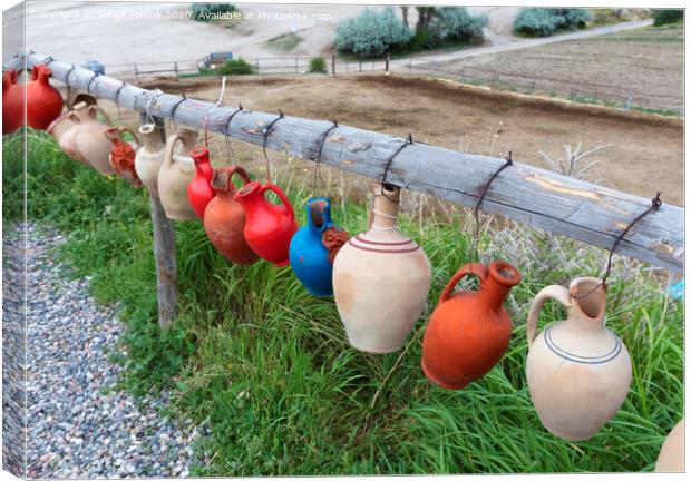 The multi-colored clay pots of desires hang tied on a wooden crossbar in Cappadocia. Canvas Print by Sergii Petruk