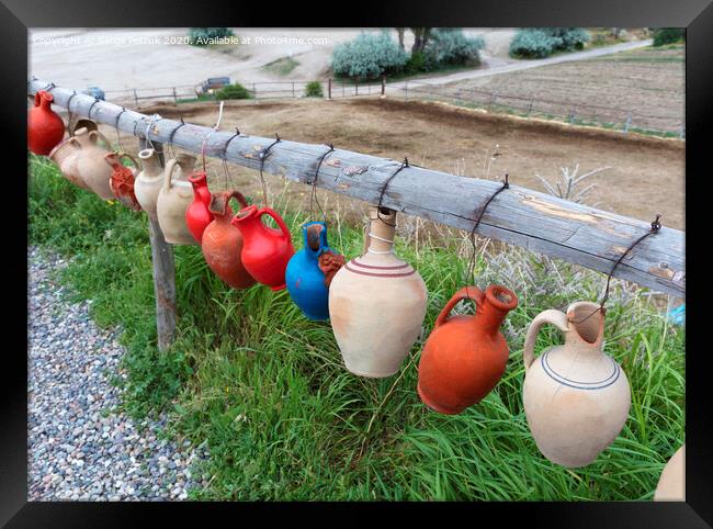 The multi-colored clay pots of desires hang tied on a wooden crossbar in Cappadocia. Framed Print by Sergii Petruk