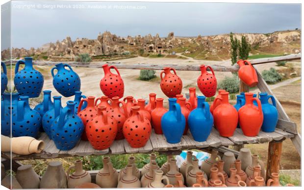 The multi-colored clay pots of desires stand on a wooden table in Cappadocia. Canvas Print by Sergii Petruk