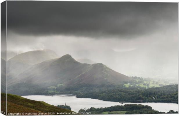 Stunning epic landscape image across Derwentwater valley with falling rain drifting across the mountains causing pokcets of light and dark across the countryside Canvas Print by Matthew Gibson