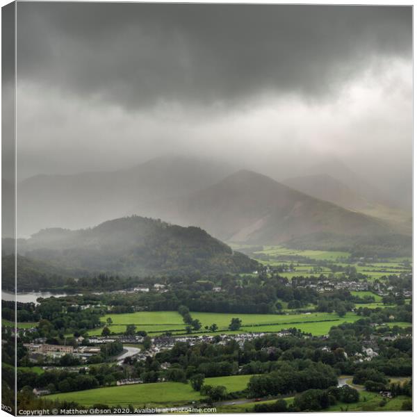 Stunning epic landscape image across Derwentwater valley with falling rain drifting across the mountains causing pokcets of light and dark across the countryside Canvas Print by Matthew Gibson