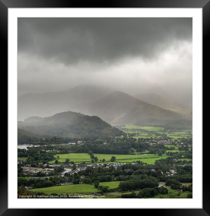 Stunning epic landscape image across Derwentwater valley with falling rain drifting across the mountains causing pokcets of light and dark across the countryside Framed Mounted Print by Matthew Gibson