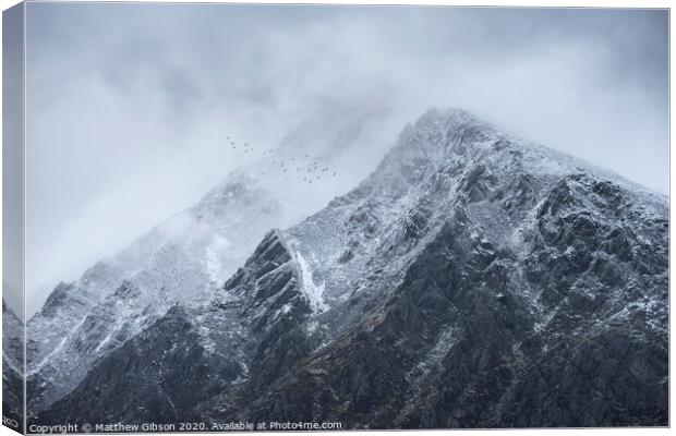 Stunning detail landscape images of snowcapped Pen Yr Ole Wen mountain in Snowdonia during dramatic moody Winter storm with birds flying high above Canvas Print by Matthew Gibson