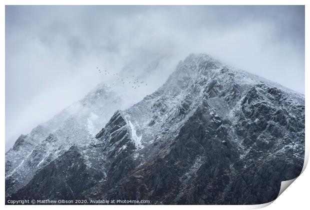 Stunning detail landscape images of snowcapped Pen Yr Ole Wen mountain in Snowdonia during dramatic moody Winter storm with birds flying high above Print by Matthew Gibson
