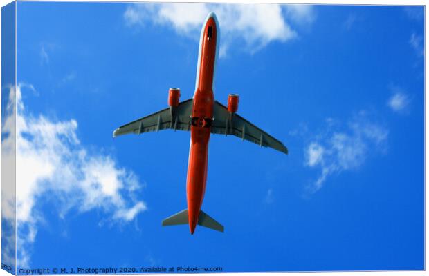 Passenger red airplane in the clouds and blue sky. Canvas Print by M. J. Photography