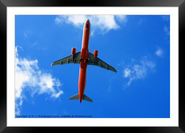 Passenger red airplane in the clouds and blue sky. Framed Mounted Print by M. J. Photography