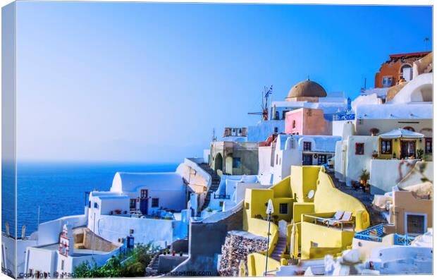 At dusk the sun bathes the traditional and colorful Greek houses in the town of Oia Canvas Print by Mario Koufios