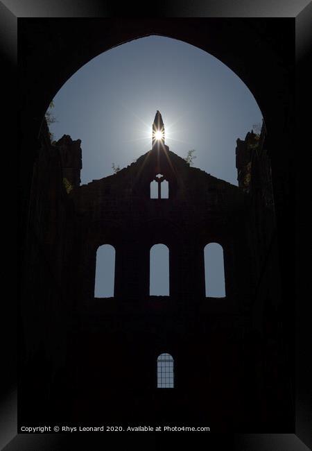 Sun flares through opening in the peak of a ruined wall of kirkstall abbey Framed Print by Rhys Leonard