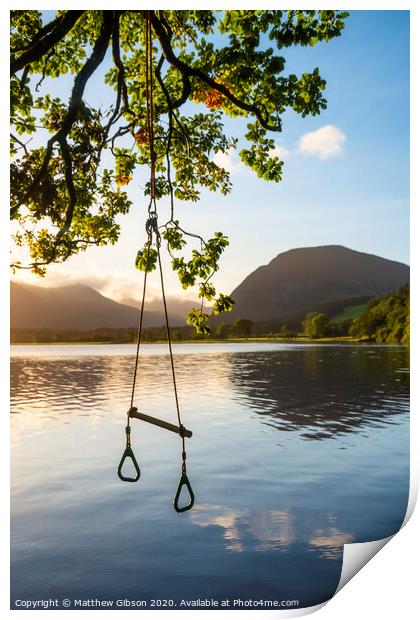 Quintessential beautiful English Summer landscape image of child's rope swing over calm lake in Lake District during golden Summer sunrise Print by Matthew Gibson