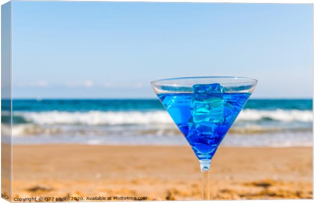 drink in a martini glass on the background of the waves affecting the sandy beach, relax on the beach, refreshing drink during the holidays Canvas Print by Q77 photo