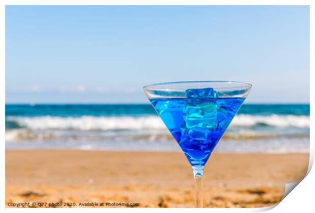 drink in a martini glass on the background of the waves affecting the sandy beach, relax on the beach, refreshing drink during the holidays Print by Q77 photo