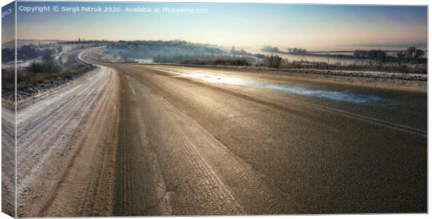 An old asphalt road is illuminated by sunshine in the winter morning. Canvas Print by Sergii Petruk