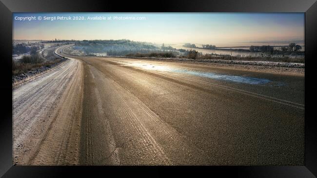 An old asphalt road is illuminated by sunshine in the winter morning. Framed Print by Sergii Petruk