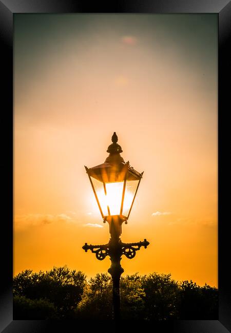 the setting sun behind a street light in Knaresborough Framed Print by mike morley