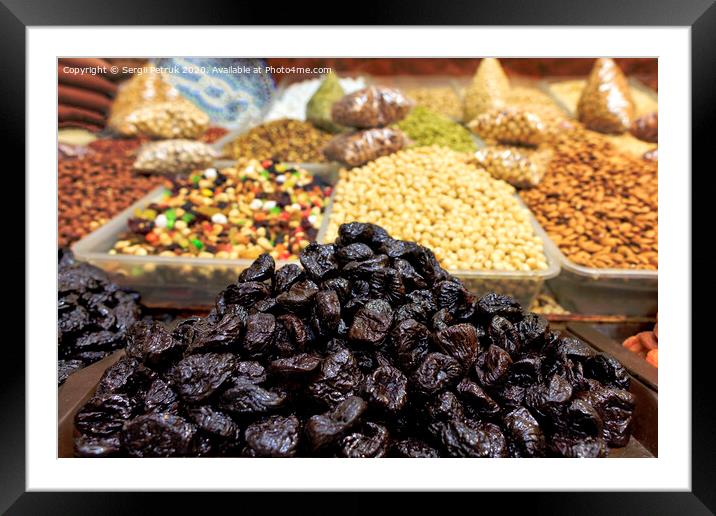 Hill of prunes on the background of various nuts in a blur. Framed Mounted Print by Sergii Petruk
