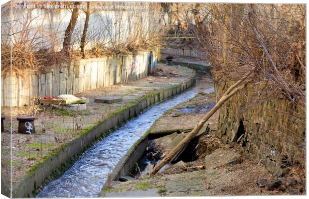 The dirty river Lybid flows along a channel enclosed in a concrete chute. Canvas Print by Sergii Petruk