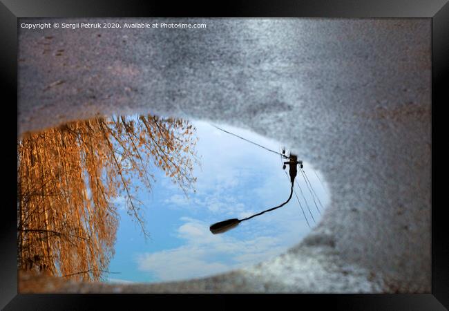 Reflection of the sky, the silhouette of a street lamp and a tree sunlit in a puddle on asphalt. Framed Print by Sergii Petruk