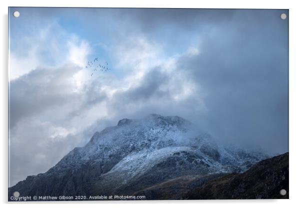 Stunning moody dramatic Winter landscape image of snowcapped Tryfan mountain in Snowdonia with stormy weather brooding overhead with birds flying high above Acrylic by Matthew Gibson