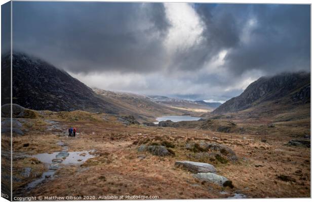 Hikers in Ogwen Valley Winter landscape with snowcapped Pen Yr Ole Wen and Tryfan mountains Canvas Print by Matthew Gibson