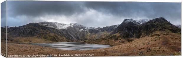 Beautiful moody Winter landscape image of Llyn Idwal and snowcapped Glyders Mountain Range in Snowdonia Canvas Print by Matthew Gibson