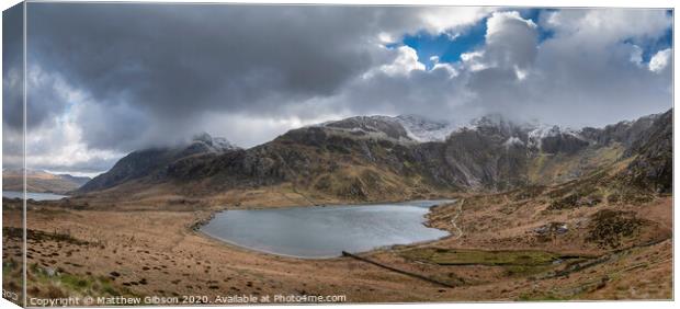 Beautiful moody Winter landscape image of Llyn Idwal and snowcapped Glyders Mountain Range in Snowdonia Canvas Print by Matthew Gibson