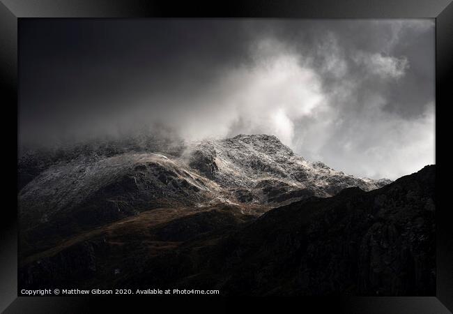 Stunning moody dramatic Winter landscape image of snowcapped Tryfan mountain in Snowdonia with stormy weather brooding overhead Framed Print by Matthew Gibson