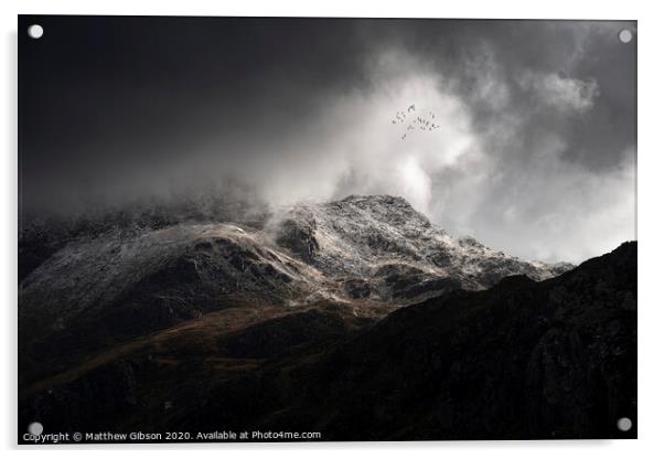 Stunning moody dramatic Winter landscape image of snowcapped Tryfan mountain in Snowdonia with stormy weather brooding overhead with birds flying high above Acrylic by Matthew Gibson