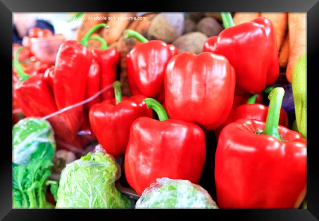 Large red sweet bell peppers on the background of other vegetables sold on the market Framed Print by Sergii Petruk