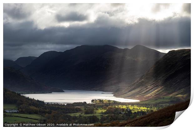 Majestic sun beams light up Crummock Water in epic Autumn Fall landscape image with Mellbreak and Grasmoor  Print by Matthew Gibson