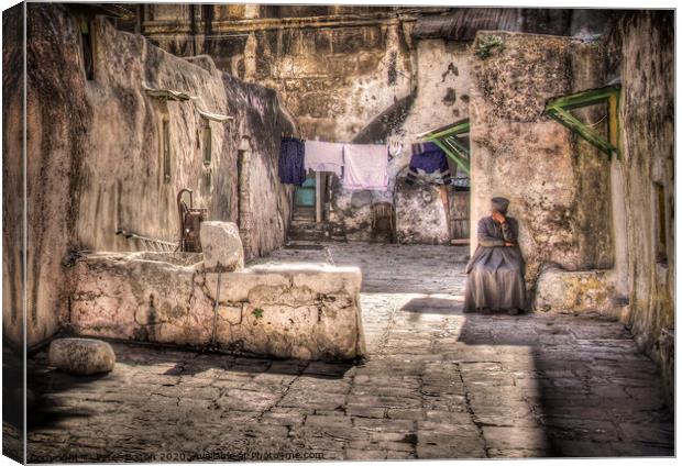 A backyard in Jerusalem old city with a resident sitting in deep contemplation.  Canvas Print by Peter Bolton