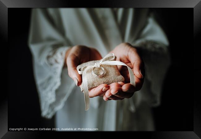Wedding rings on a pad held by the delicate hands of a bride. Framed Print by Joaquin Corbalan