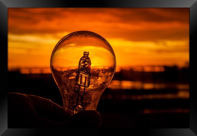Light bulb in hand against colorful sunrise  Framed Print by Miro V