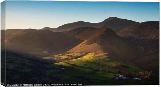 Beautiful Autumn Fall landscape image of sun beams lighting up small area of mountain side in Lake District whilst rest of area is in darkness with Robinson and Dale Head in background Canvas Print by Matthew Gibson