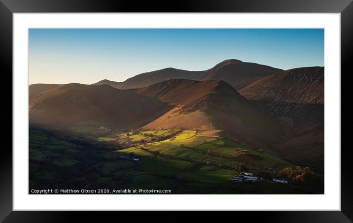 Beautiful Autumn Fall landscape image of sun beams lighting up small area of mountain side in Lake District whilst rest of area is in darkness with Robinson and Dale Head in background Framed Mounted Print by Matthew Gibson