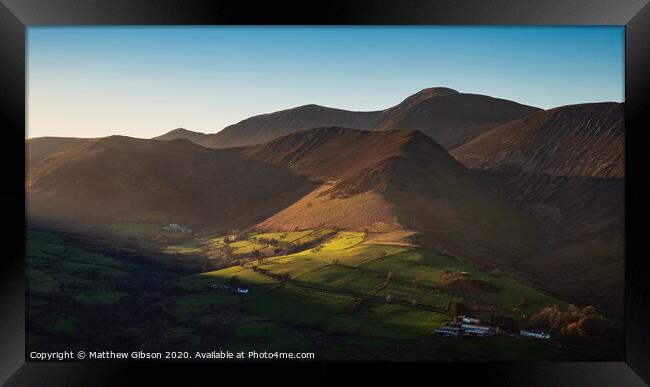 Beautiful Autumn Fall landscape image of sun beams lighting up small area of mountain side in Lake District whilst rest of area is in darkness with Robinson and Dale Head in background Framed Print by Matthew Gibson