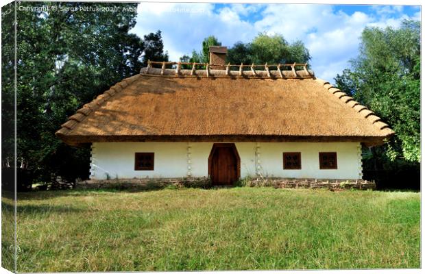 Old traditional Ukrainian rural house with thatched roof and wicker fence in the garden Canvas Print by Sergii Petruk