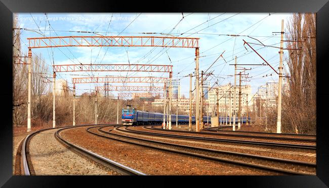 Passenger train cars of the train ride on the railway tracks in the background of the cityscape Framed Print by Sergii Petruk