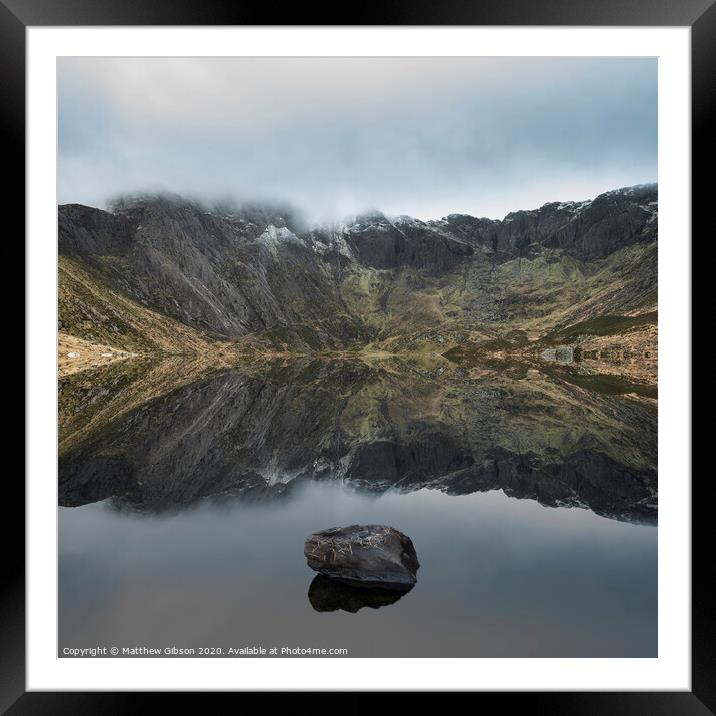 Beautiful moody Winter landscape image of Llyn Idwal and snowcapped Glyders Mountain Range in Snowdonia Framed Mounted Print by Matthew Gibson