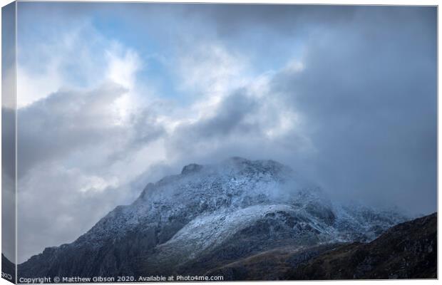 Stunning moody dramatic Winter landscape image of snowcapped Tryfan mountain in Snowdonia with stormy weather brooding overhead Canvas Print by Matthew Gibson